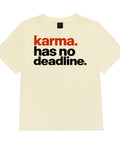 Karma Has No Deadline women's heavyweight garment-dyed tee in Buttermilk – front with rust-orange and black lettering, product view 2