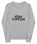 Athletic Heather Stay Curious youth long-sleeve tee with one black magnifying-glass lettering design on the front.